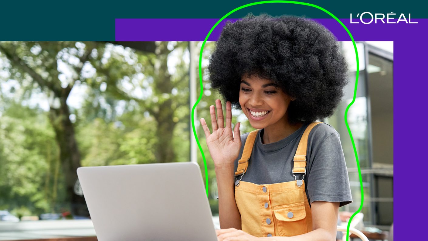 Woman smiling and waving at her laptop screen
