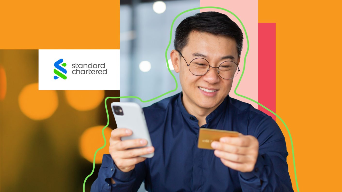 Man with glasses holding smartphone while looking at his payment card