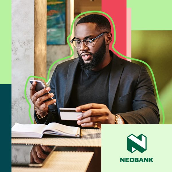 Man sitting at a table, holding credit card and watching his phone