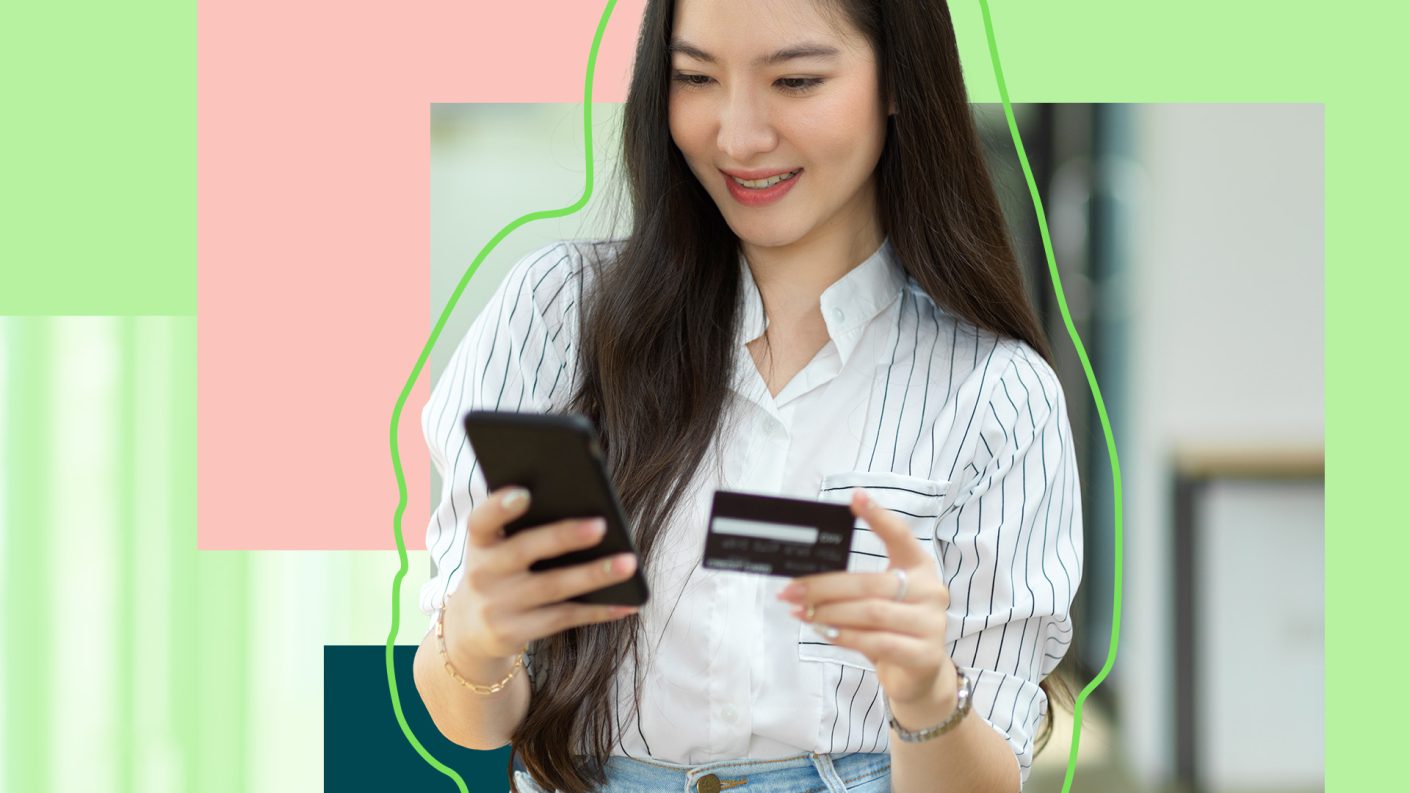 Young woman holding her smartphone and bank card