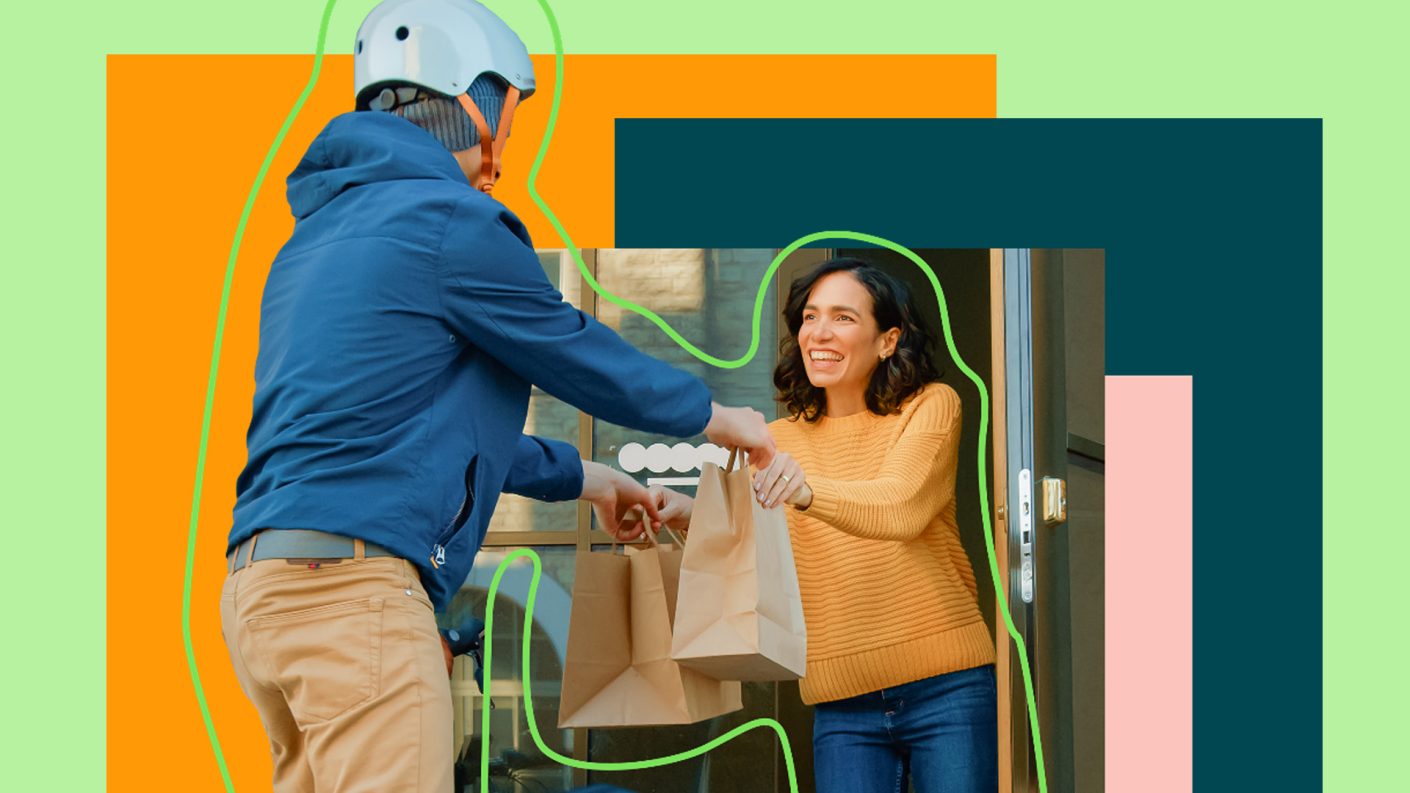 Delivery person handing over brown bags to another person at the door