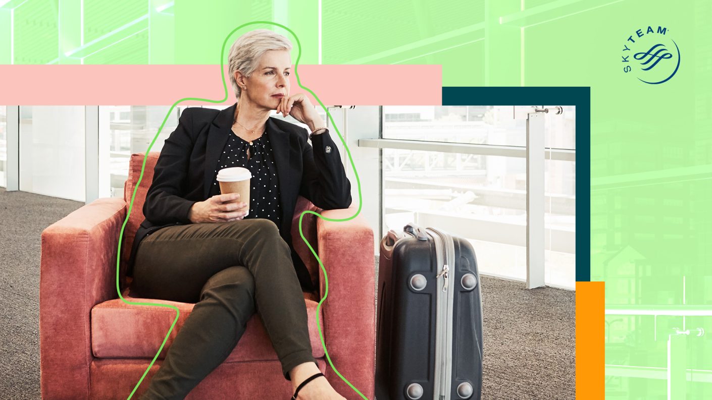 Lady with a cup of coffee and suitcase waiting in airport