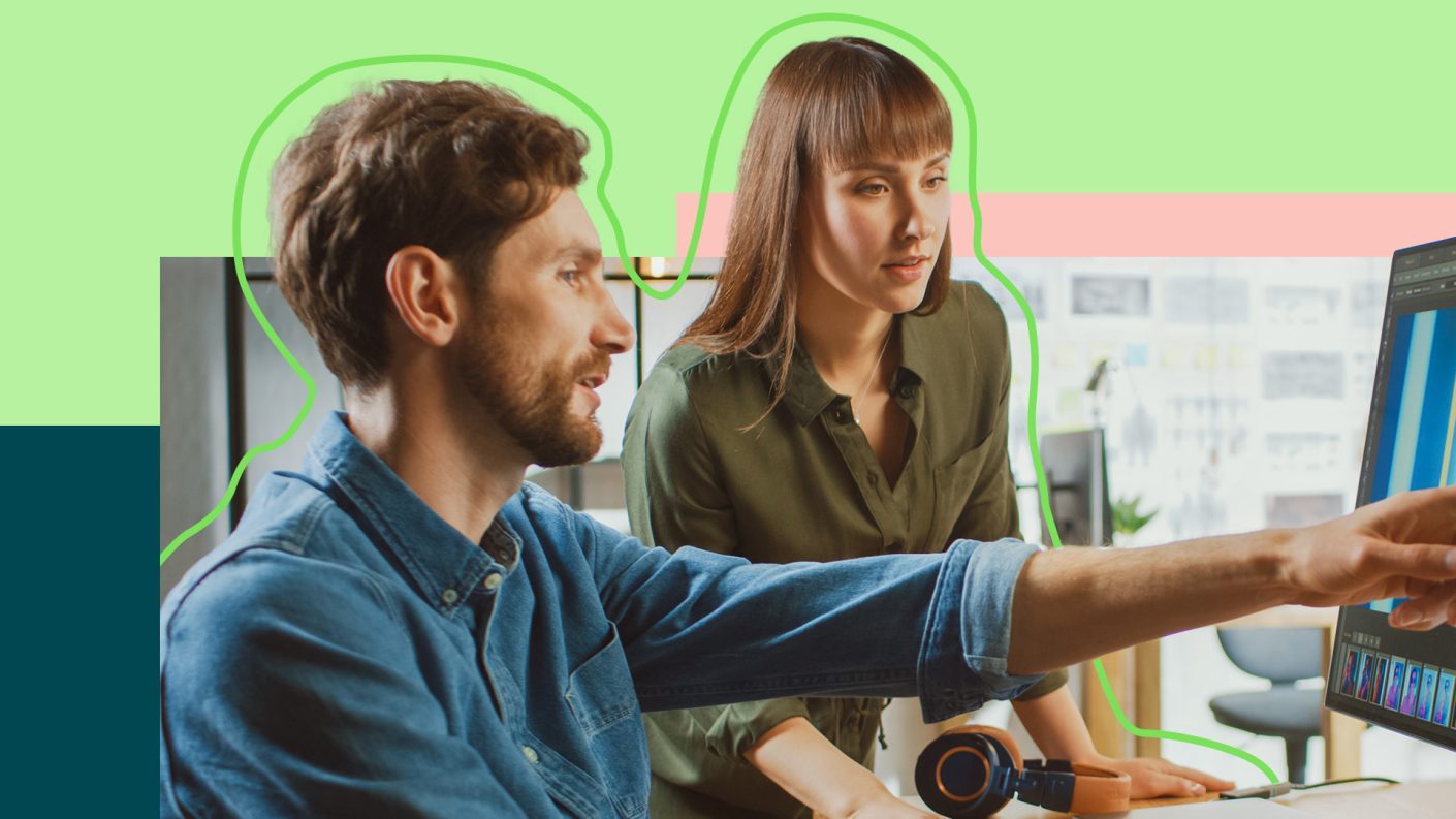 Two people collaborating, male pointing at computer screen