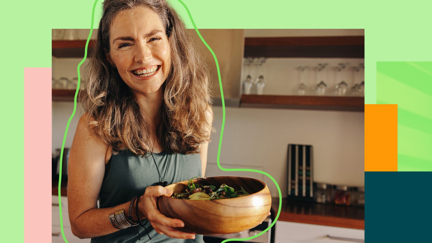 Smiling woman holding a wooden bowl filled with vegetables