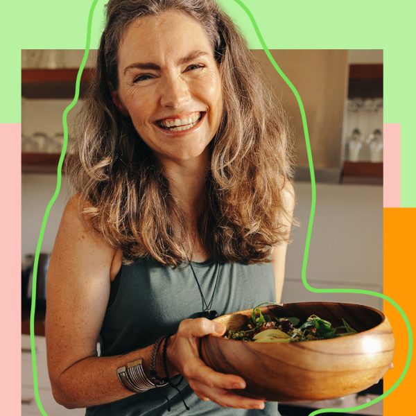 Smiling woman holding a wooden bowl filled with vegetables