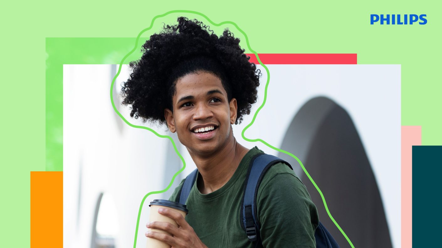 Young guy with curly hair holding a cup of coffee