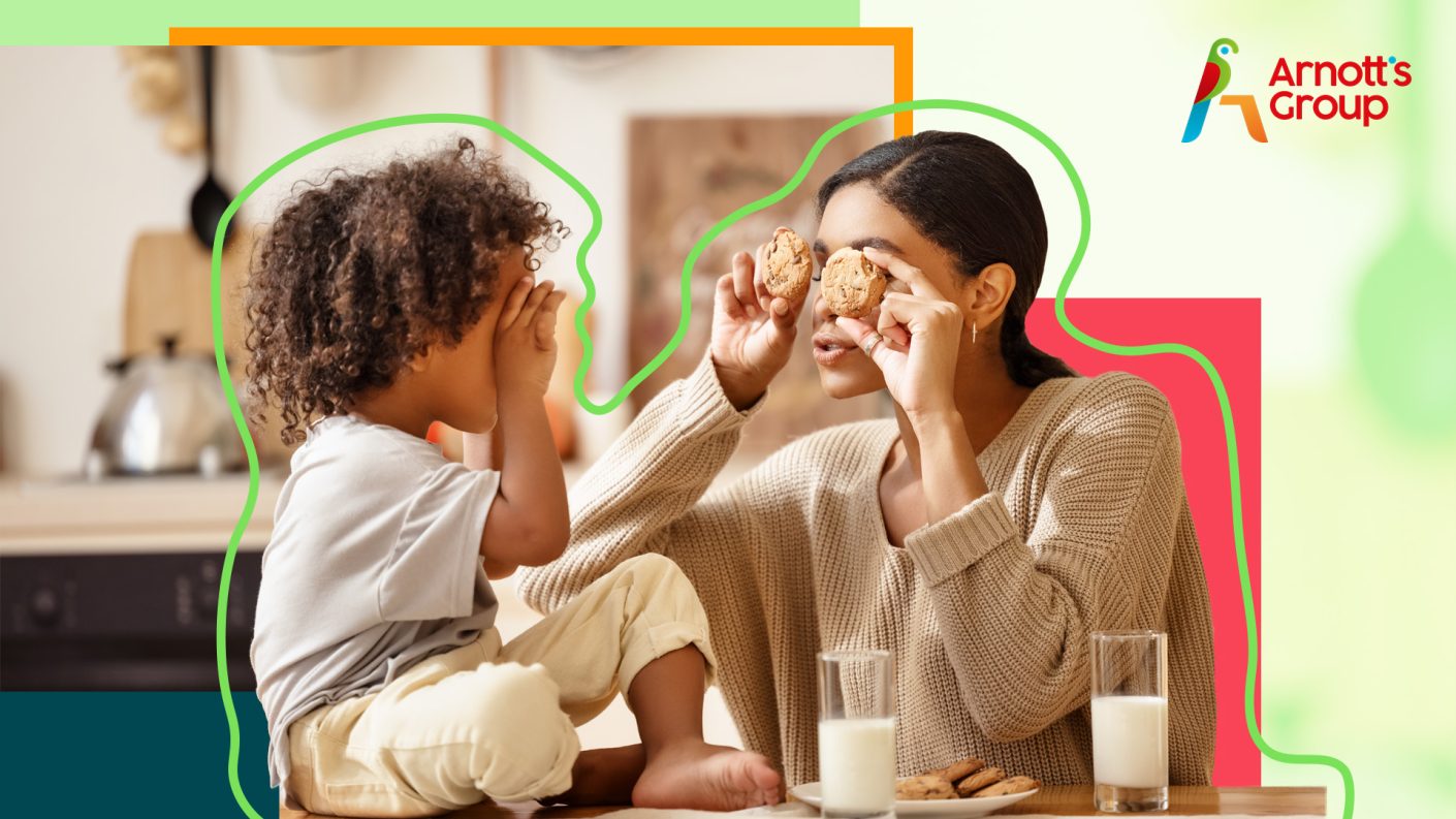 A young woman and her child holding cookies in front of their eyes