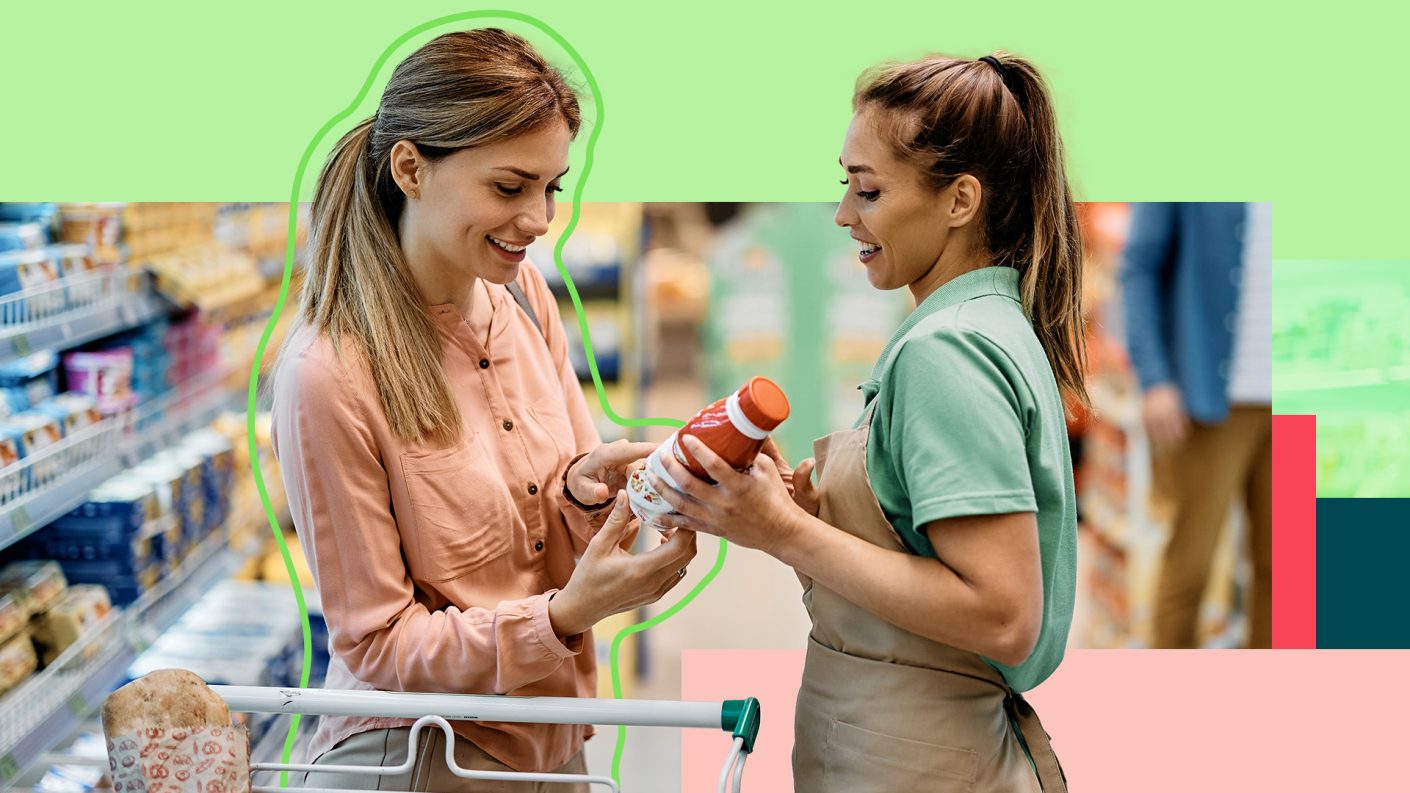 Two women in the supermarket talking over a bottle