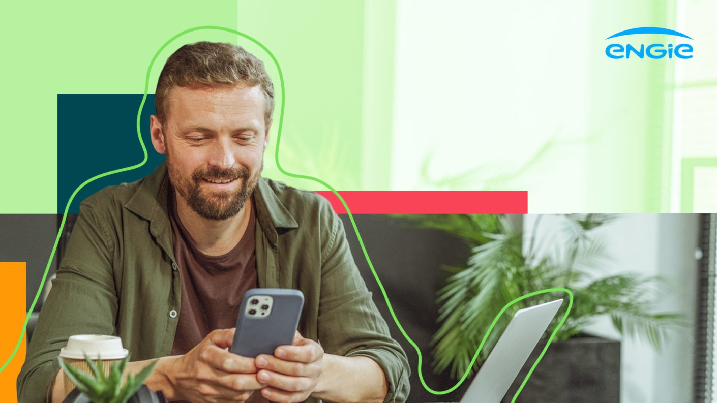 Man looking at his smartphone next to laptop