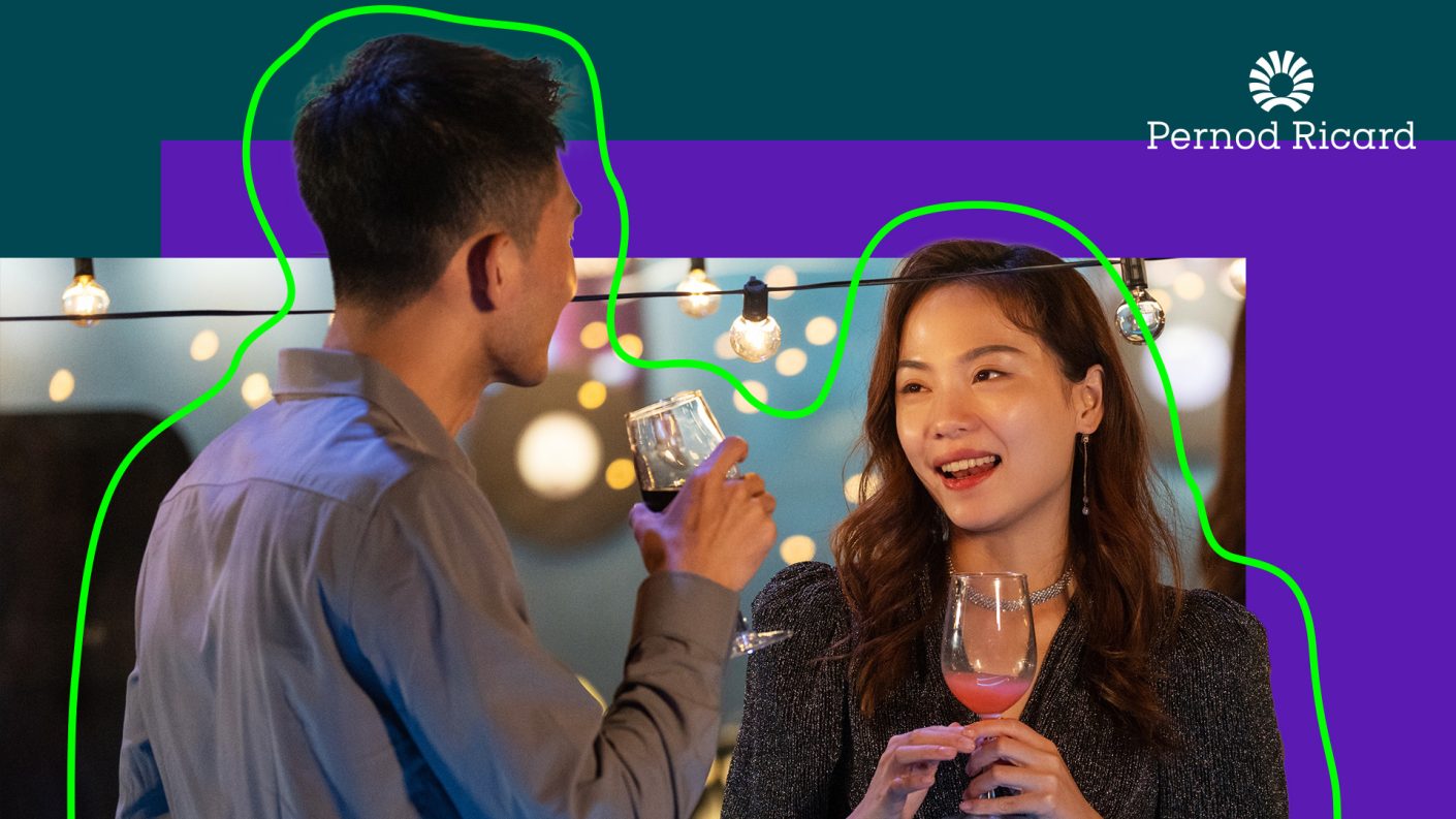 Male and female holding a drink, talking at a party