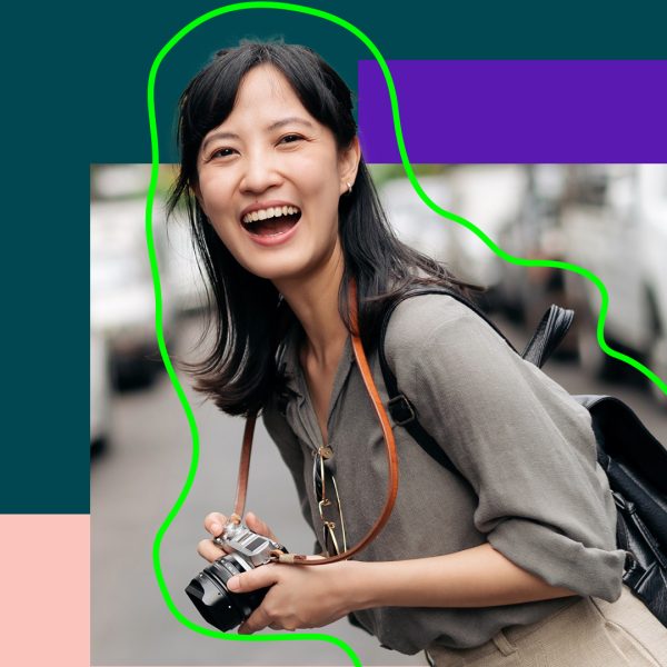 Woman in the street with camera around her neck smiling
