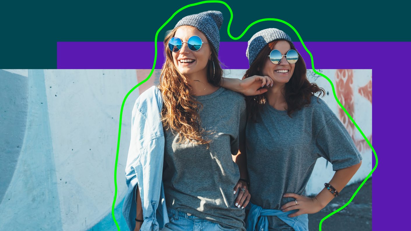 Two girls wearing beanies and sunglasses, dressed similar.