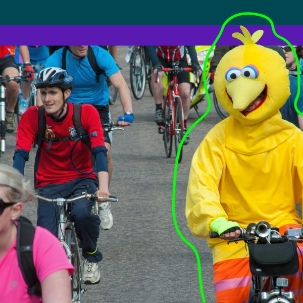 Man in costume riding bike surrounded by cyclists in normal clothing.