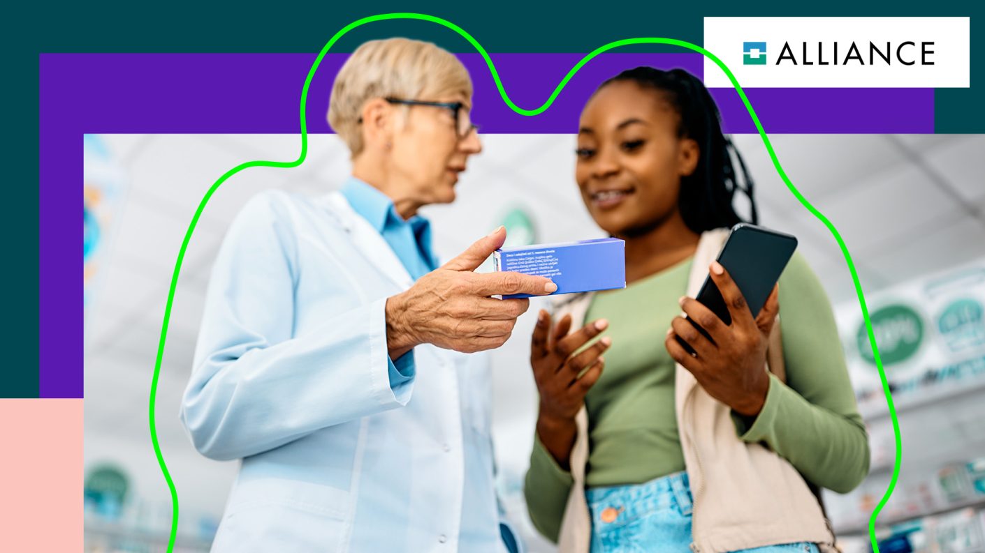 Pharmacist handing blue box to girl holding a cellphone.