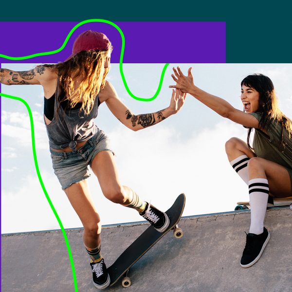 girl skateboarding on ramp while high fiving friend