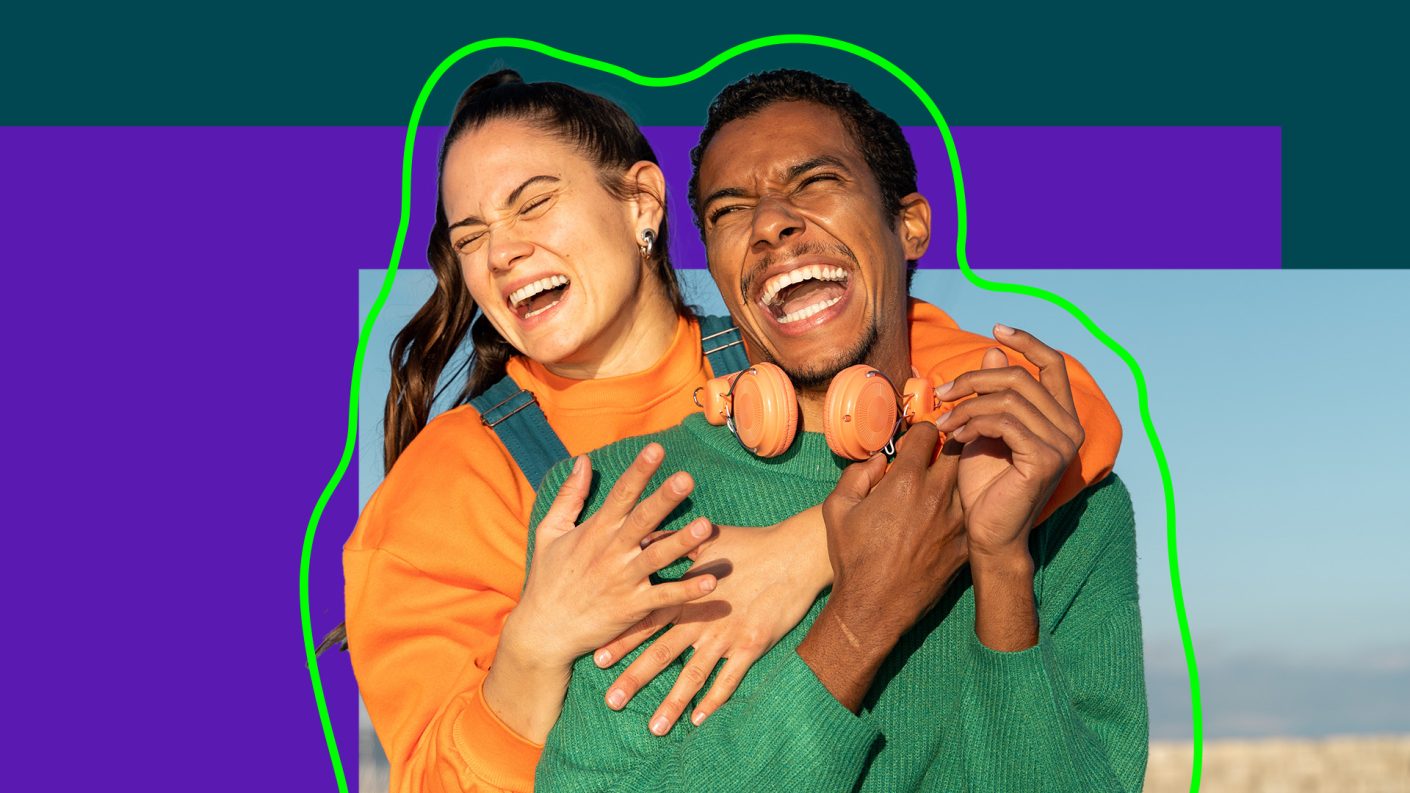 A woman standing behind a man, hugging eachother.