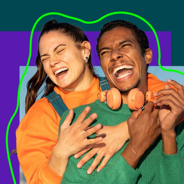 A woman standing behind a man, hugging eachother.