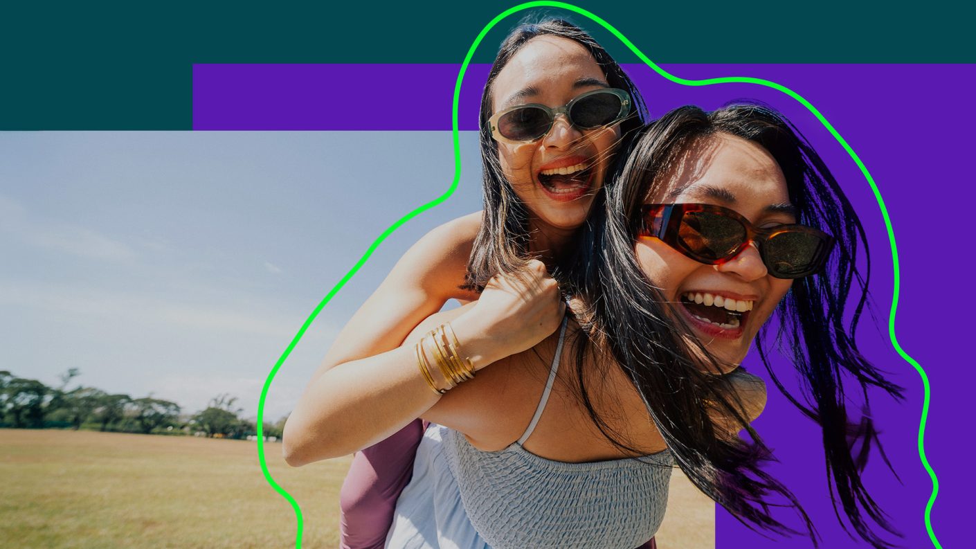 Two women wearing sunglasses, laughing