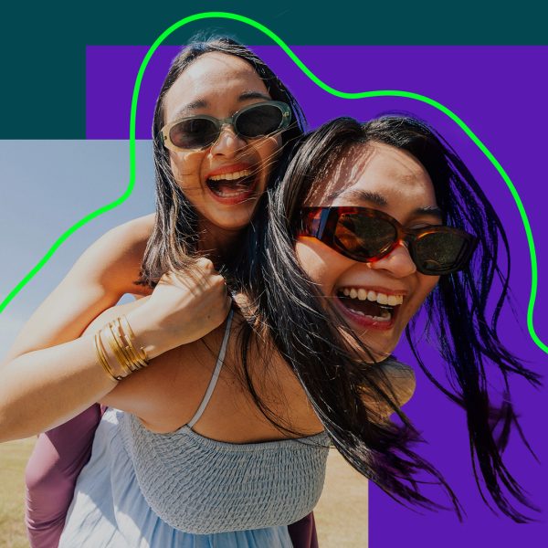 Two women wearing sunglasses, laughing