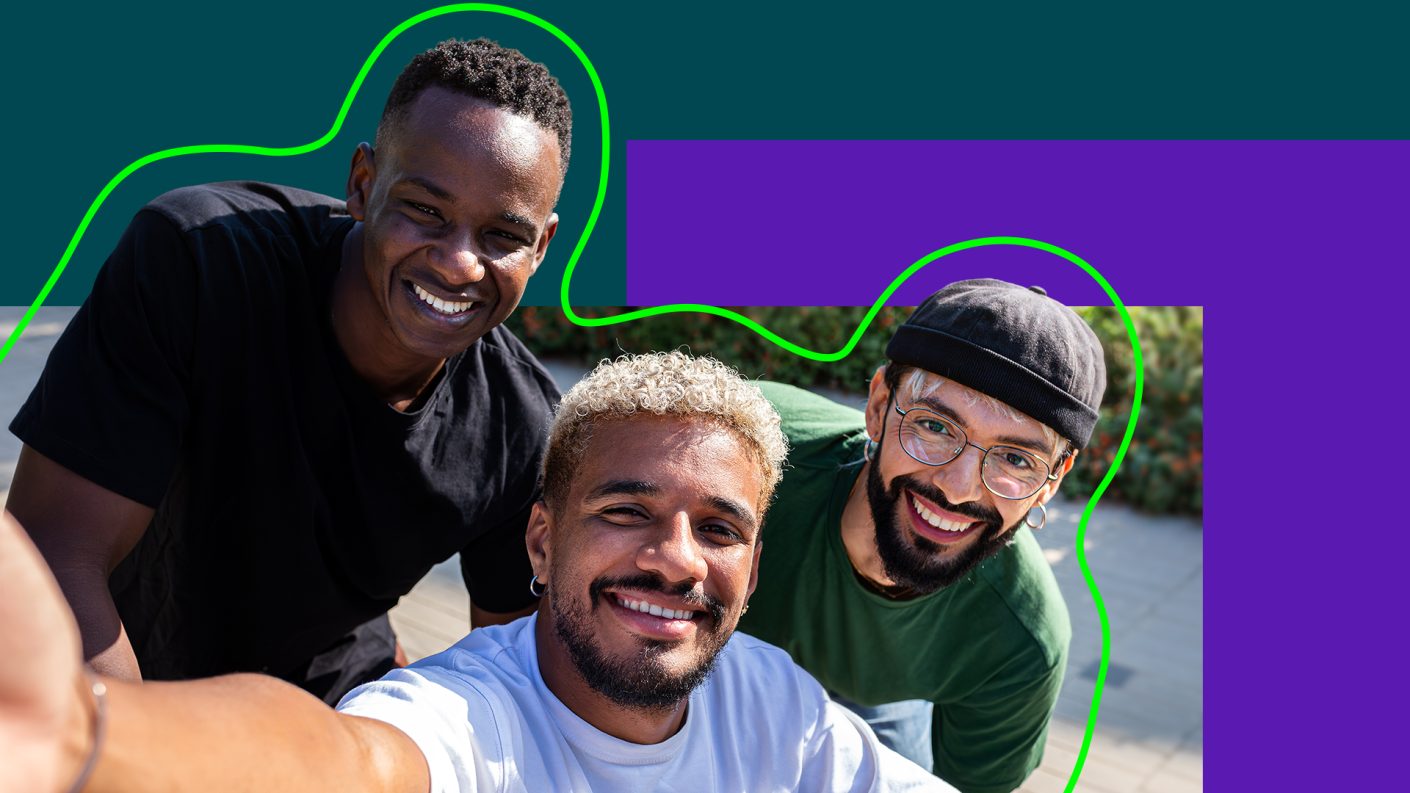 Three guys looking taking a selfie, one in a wheelchair
