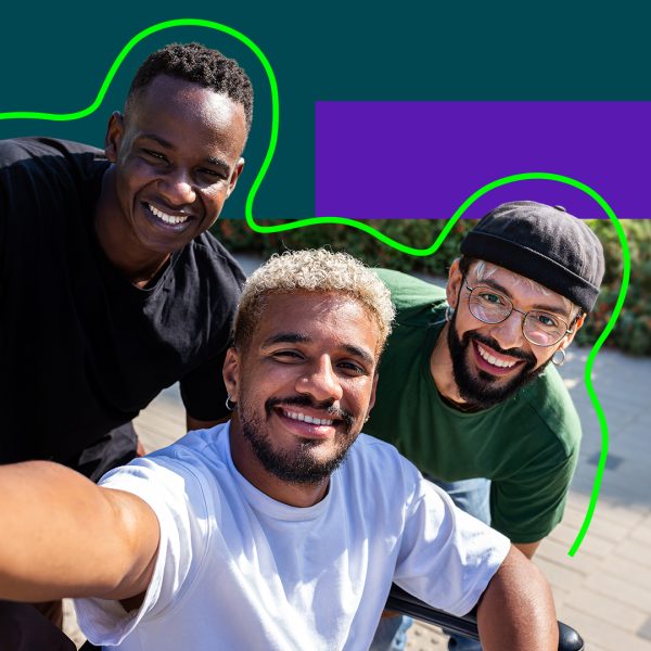 Three guys looking taking a selfie, one in a wheelchair